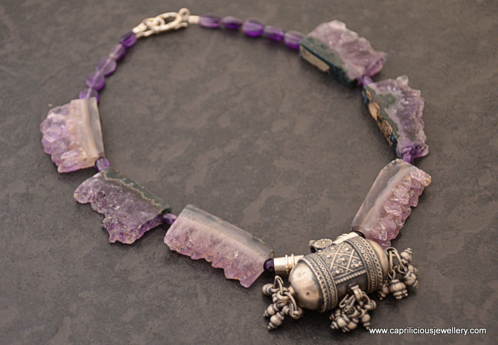 A necklace of rectangular amethyst geodes and a silver amulet by Caprilicious Jewellery
