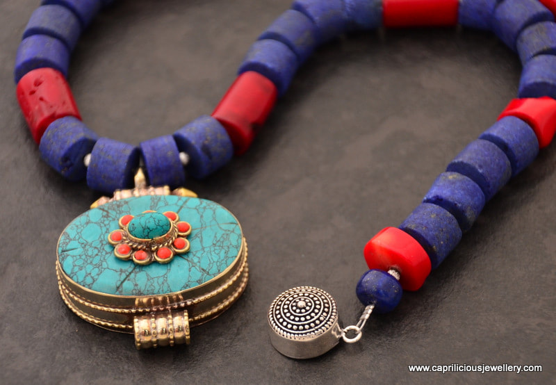 Matte cylinders of lapis lazuli, coral and a turquoise and coral ghau box pendant by Caprilicious Jewellery