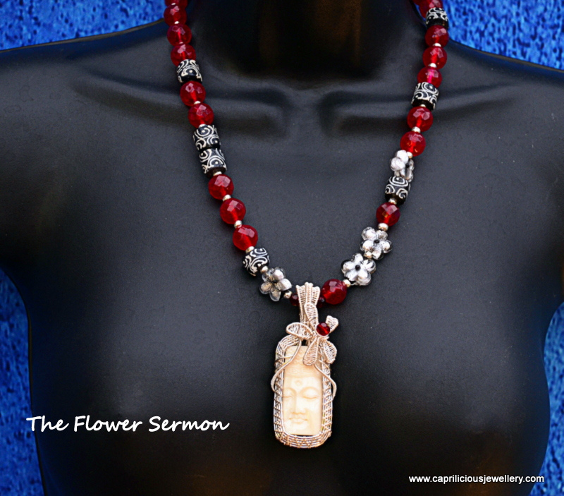 The Flower Sermon, an ox bone pendant with a Buddha set in hand made wire work by Caprilicious Jewellery in a red quartz/Krobo bead necklace